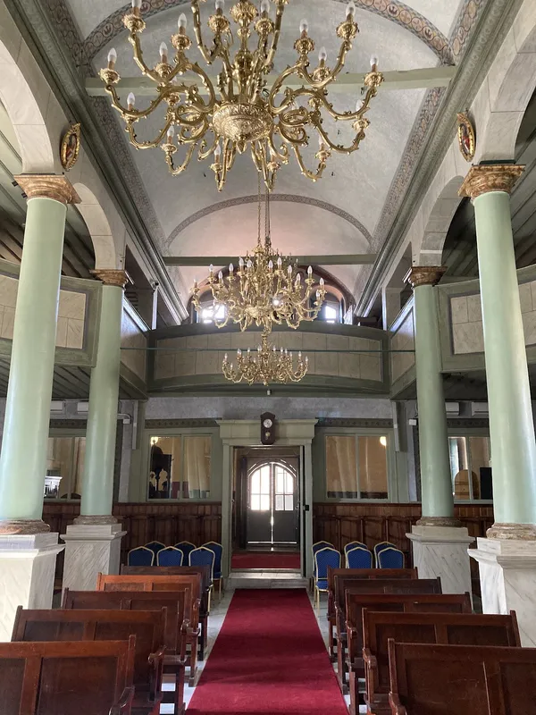 Büyük avizeler ve yeşil sütunlarla süslenmiş zarif bir ortodoks kilisesi iç mekanı.