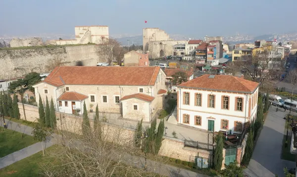 Tarihi bölgedeki beyaz duvarlı bina ve yeşil alanlar.