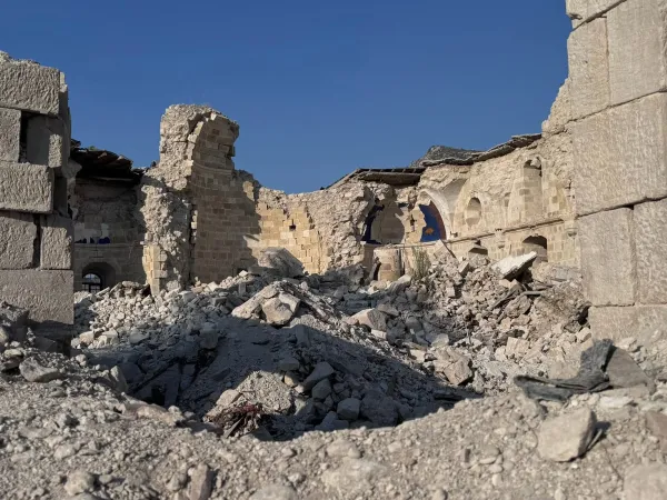 Yıkık bir ortodoks kilisesinin kalıntıları, çökmüş çatılar ve taş duvarlarla dolu bir sahne.