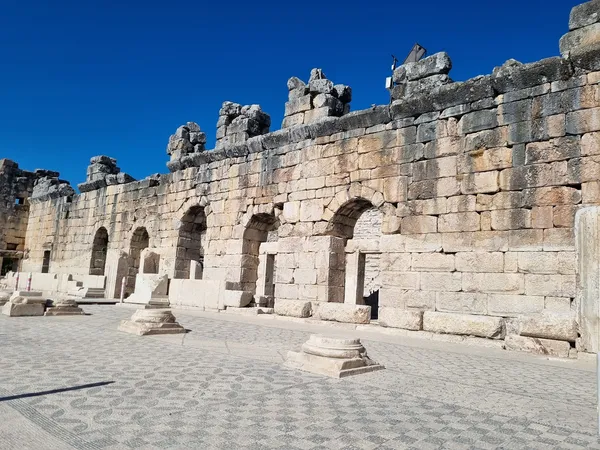 Antik yapının kalıntıları, yüksek taş duvar ve sütunlar görünmekte.