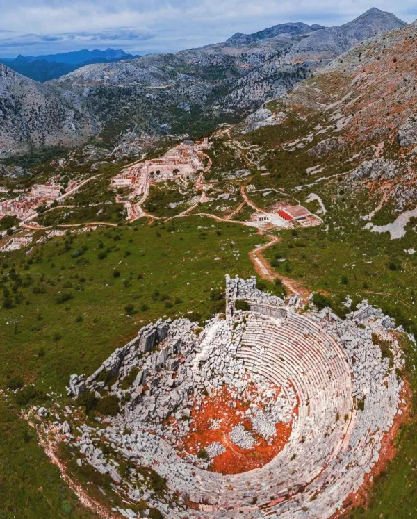 Dağlık alanda yer alan antik tiyatro kalıntıları ve çevresindeki yeşil alanlar