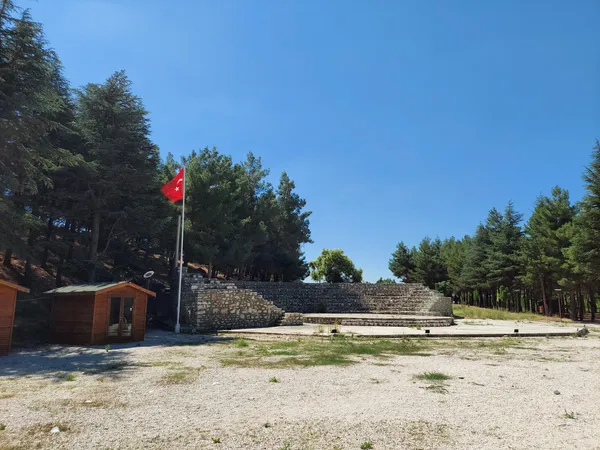 Yeşil ağaçlarla çevrili tarihi bir yapı ve amfi tiyatro görünümü.