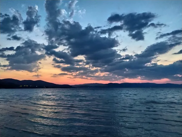 Huzur verici Salda Gölü manzarasında gün batımı ve dağ silüetleri.