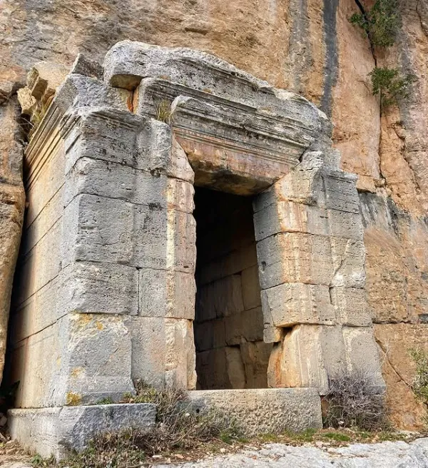 Büyük bir kayaya oyulmuş antik yapının simetrik girişi ve taş blokları