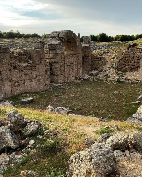 Eski taş yapılar ve yeşil alanlarla dolu tarihi bir alan manzarası.
