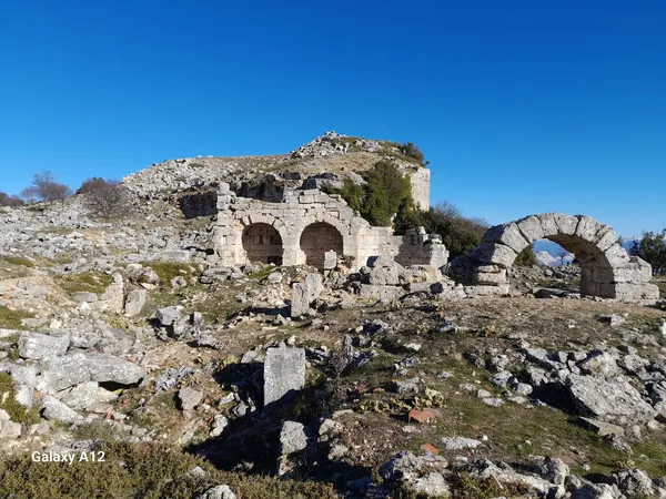 Kremna Antik Kenti'nde sıralanmış kemerli yapı kalıntıları ve doğal manzara.