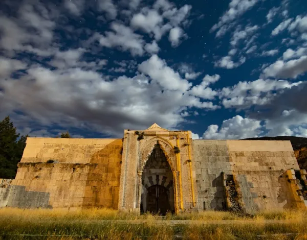 Tarihi Susuz Han'ın gece görünümü, taş duvarları ve yıldızlı gökyüzü ile mistik bir atmosfer sunuyor.