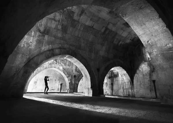 Taş duvarlar ve kemerlerle dolu tarihi bir iç mekan görüntüsü.