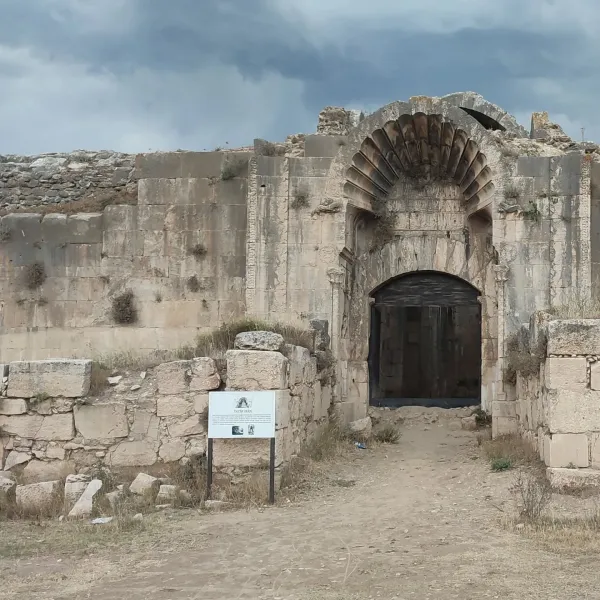 Eski bir yapının girişinde ihtişamlı kemer ve bilgilendirme tabelası