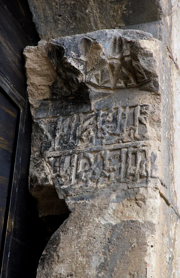 Eski yazıtlar ve kabartmalarla kaplı taş duvarın detayları