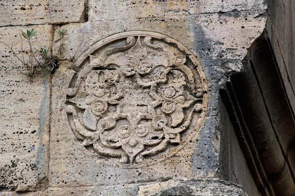 Duvarda yer alan dairesel taş işçiliği, organik desenler ve zamanla oluşmuş pürüzlerle dikkat çekiyor.