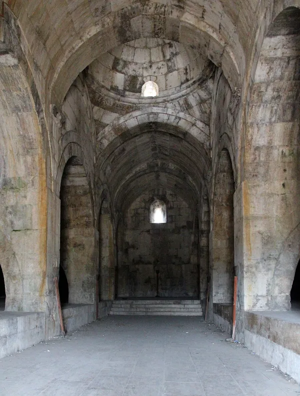 Tarihi Susuz Han'ın iç mekanında yüksek kemerler ve taş duvarlar görünmekte.