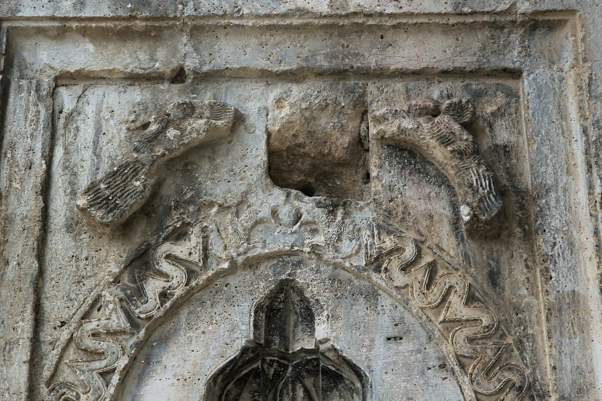 Susuz Han'da Sanatın İzleri - Kabartmalar ve Figürler! Eski taş yapıda kabartma, kuş figürleri ve dalgalı desenler yer alıyor.