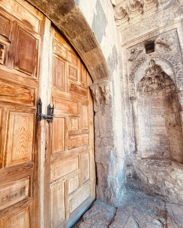 Büyük ahşap kapı ve taş duvar detaylarıyla tarihi yapı görünümü