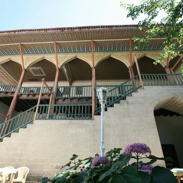 Geleneksel mimari özelliklere sahip Bakibey Konağı, kemerli açıklıklar ve mor çiçeklerle çevrili.