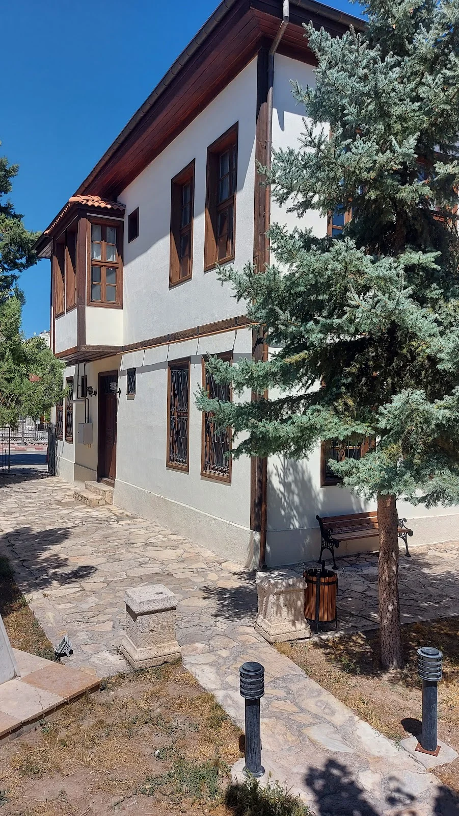 Geleneksel Türk Mimarisi - Ahşap Pencereler ve Taş Yolu! İki katlı beyaz yapı, ahşap pencereler ve taş döşeli yürüyüş yolu ile sakin bir mekân sunuyor.