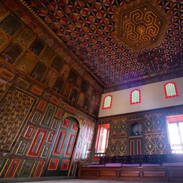 Renkli desenlerle süslenmiş tavan ve motifli duvarlar, iç mekanda zengin bir atmosfer sunuyor.