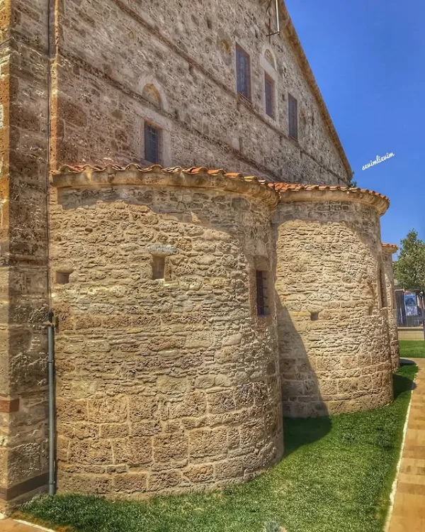 Tarihi yapının dış cephesi, doğal dokusu ve çevresindeki yeşil alan.