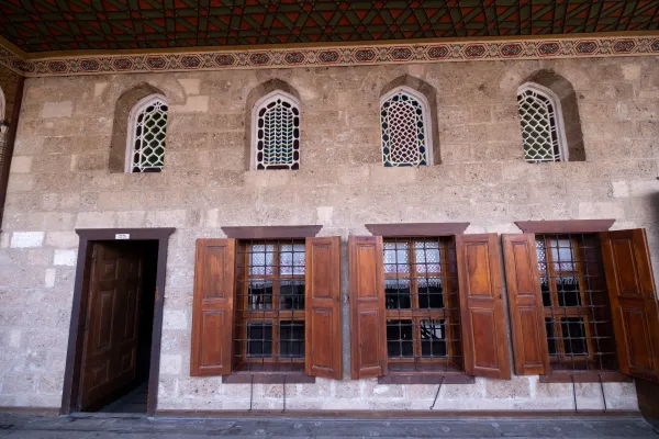 Açık tonlu taş duvar, vitray pencereler ve ahşap kapı detaylarıyla tarihi bir yapı