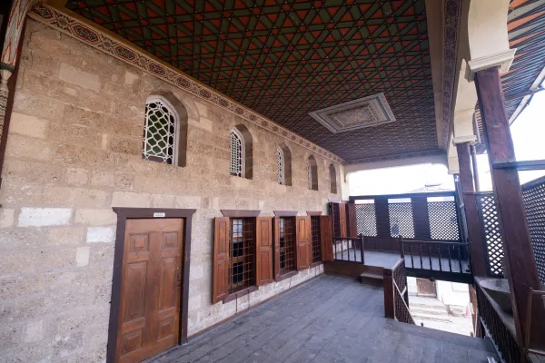 Geleneksel iç mekanda taş duvarlar, ahşap kapılar ve desenli tavan süslemesi.