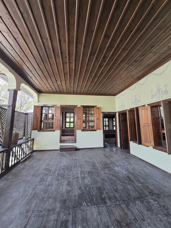 Geniş bir iç mekan, ahşap tavan ve geleneksel desenlerle süslenmiş duvarlar.