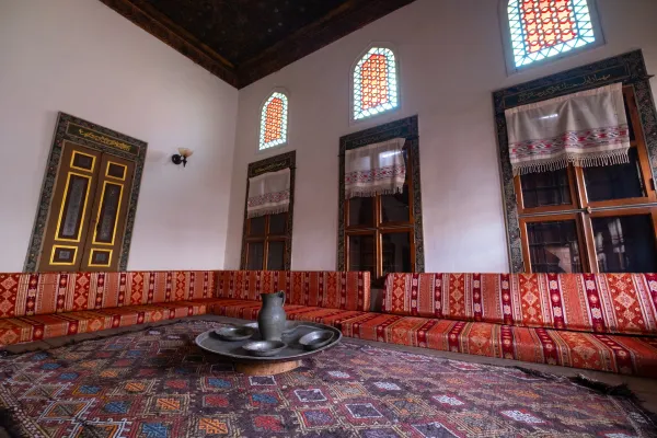 Beyaz duvarlar, yüksek tavan ve yuvarlak masa ile geleneksel oturma alanı