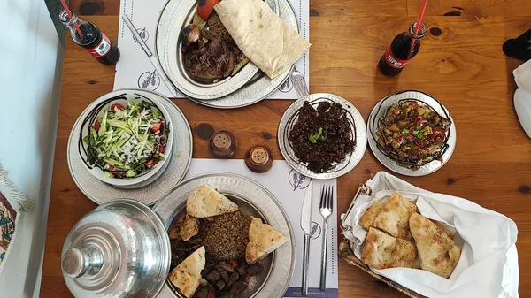 Ahşap masada zengin Türk yemekleri, salata, et, mercimek püresi ve ızgara sebzeler yer alıyor.