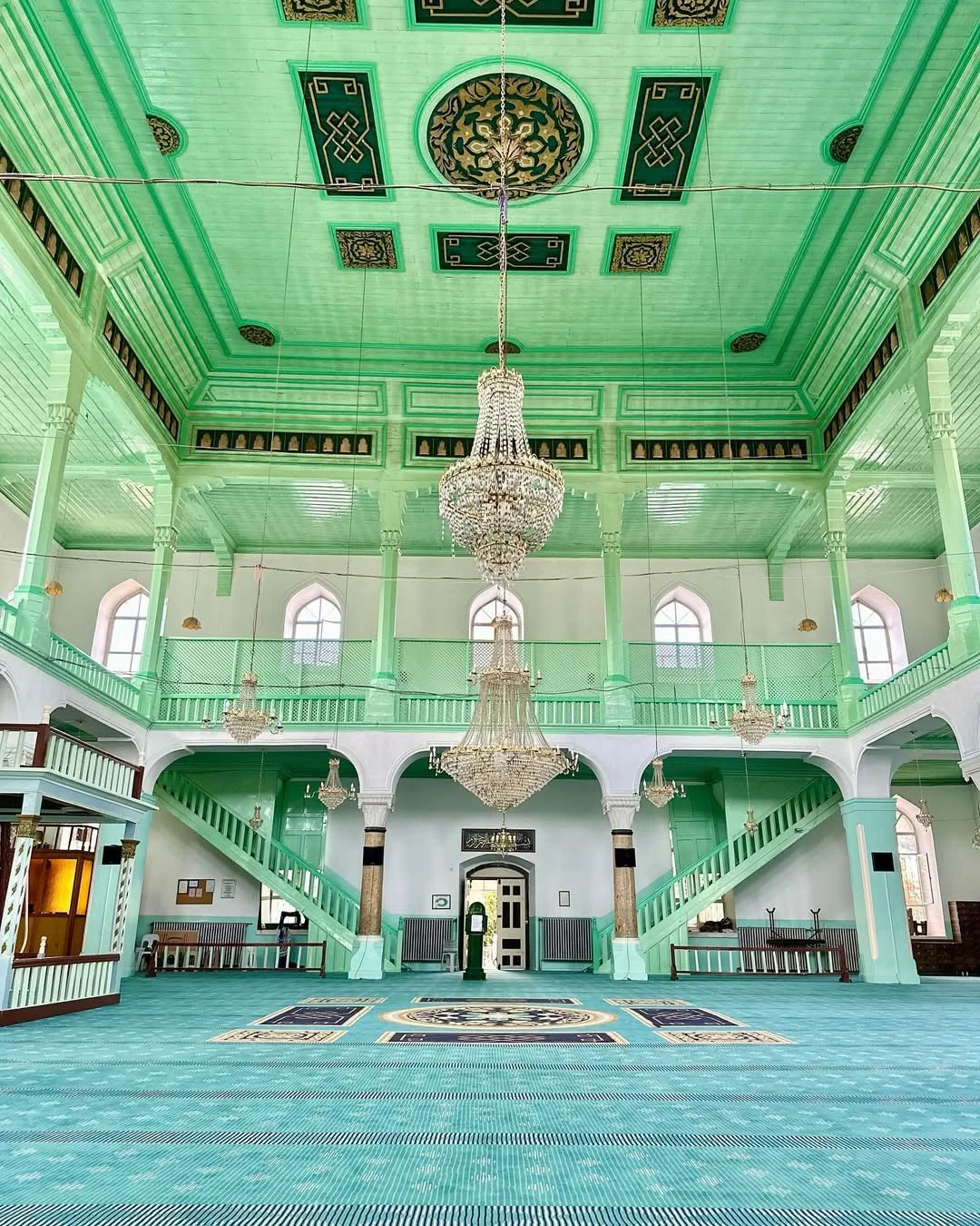 Büyüleyici İç Mekan: Ulu Camii! Yeşil tonlarında süslemeler ve avize ile geniş iç mekan Geniş bir caminin iç mekanında yeşil tonlarında süslemeler ve avize.