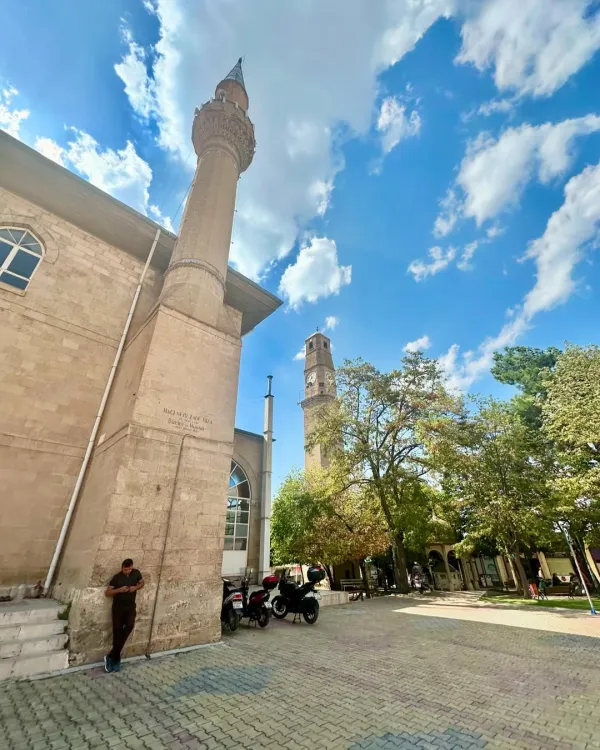 Tarihi caminin minaresi, saat kulesi ve yeşil alanın manzarası