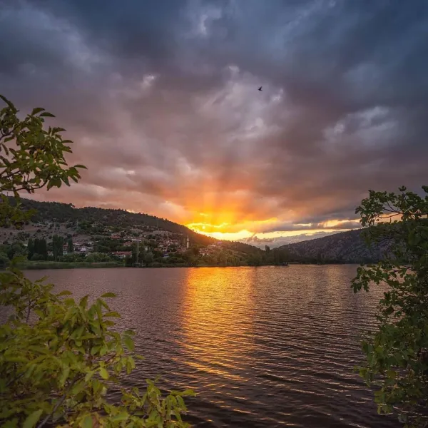Sakin göl, dağların eteklerindeki köy ve muhteşem akşam gökyüzü