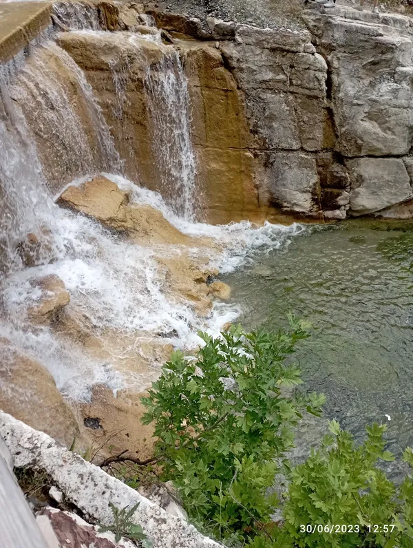 Karanlıkdere Kanyonu'nda şelaleden akan berrak su ve çevresindeki yeşil bitkiler.