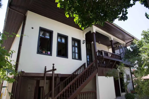 İki katlı tarihi bina, açık duvarlar ve geniş balkona sahip.