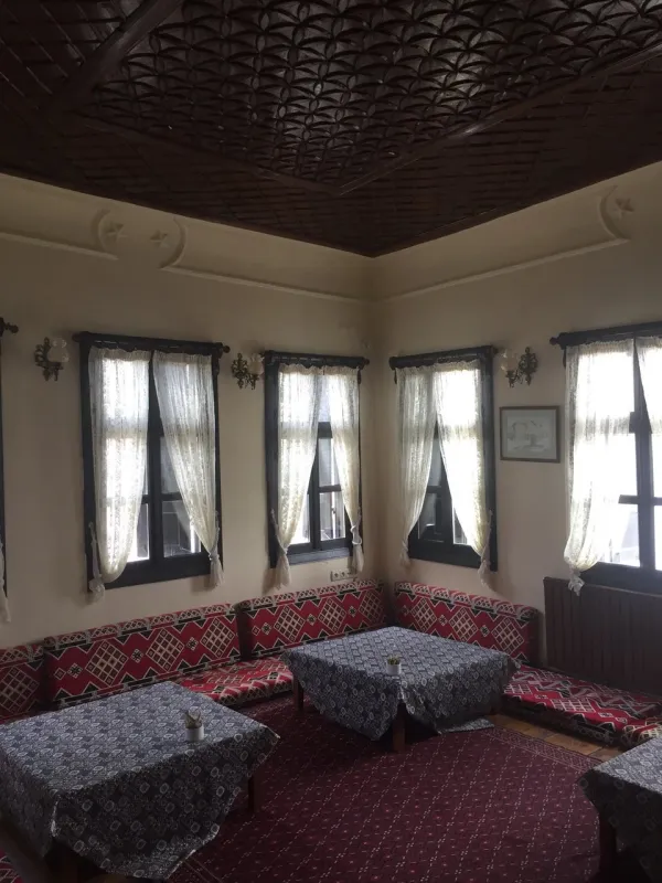 Açık tonlu duvarlar, süslü ahşap tavan ve desenli minderlerle dolu oturma alanı