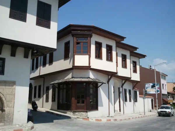 Beyaz duvarlı geleneksel bir bina, geniş pencereler ve ahşap panjurlar ile dikkat çekiyor.
