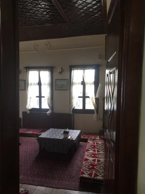 Geleneksel bir iç mekanda yer minderi ve düşük masa, zarif tavan ve pencereden gelen ışık.