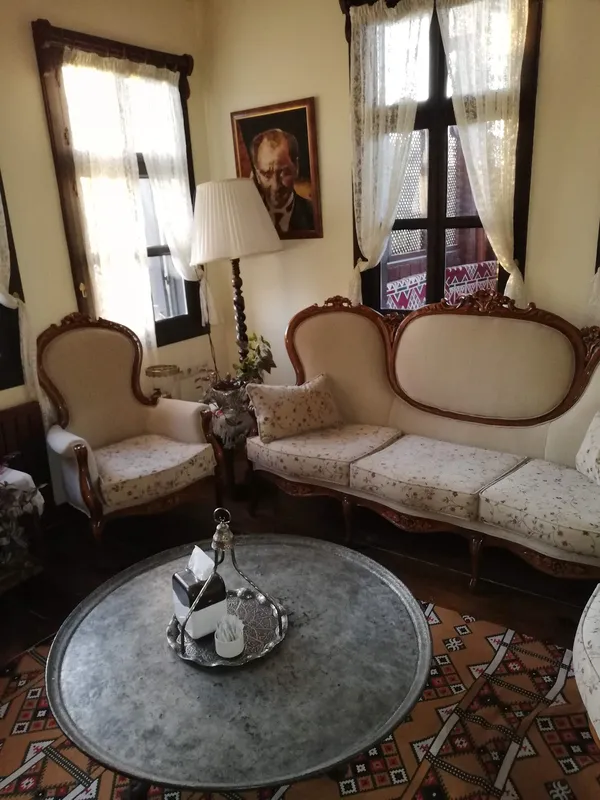 Şık koltuklar, metal tepsi ve geleneksel halı ile sıcak bir oturma alanı.