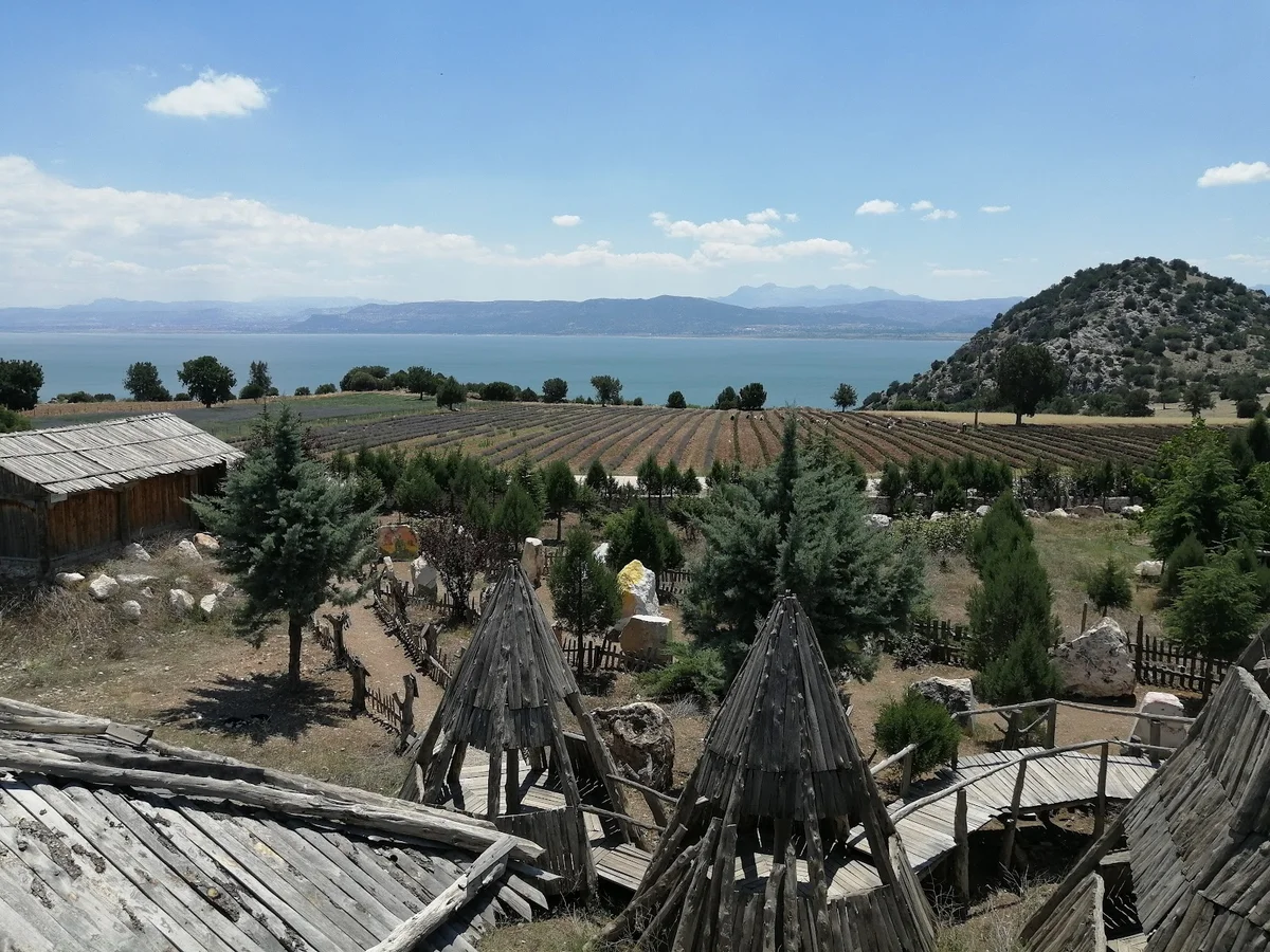 Lisinia: Huzurun Adresi - Göl, Dağlar ve Ahşap Yapılar Yemyeşil doğa manzarası, göl, dağlar ve ahşap yapılarla dolu alan.