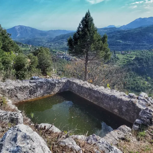 Taşlarla çevrili su birikintisi ve arka planda yeşil dağlar