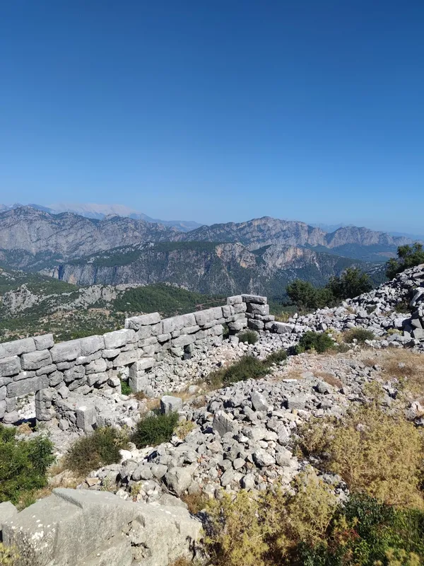 Yüksek dağlık bölgede yer alan tarihi kalıntılar ve yeşil manzara.