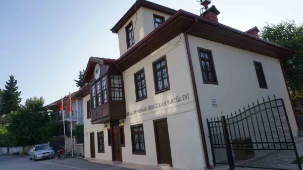 Beyaz cepheli kültür evi, büyük pencereler ve saat ile dikkat çekiyor.