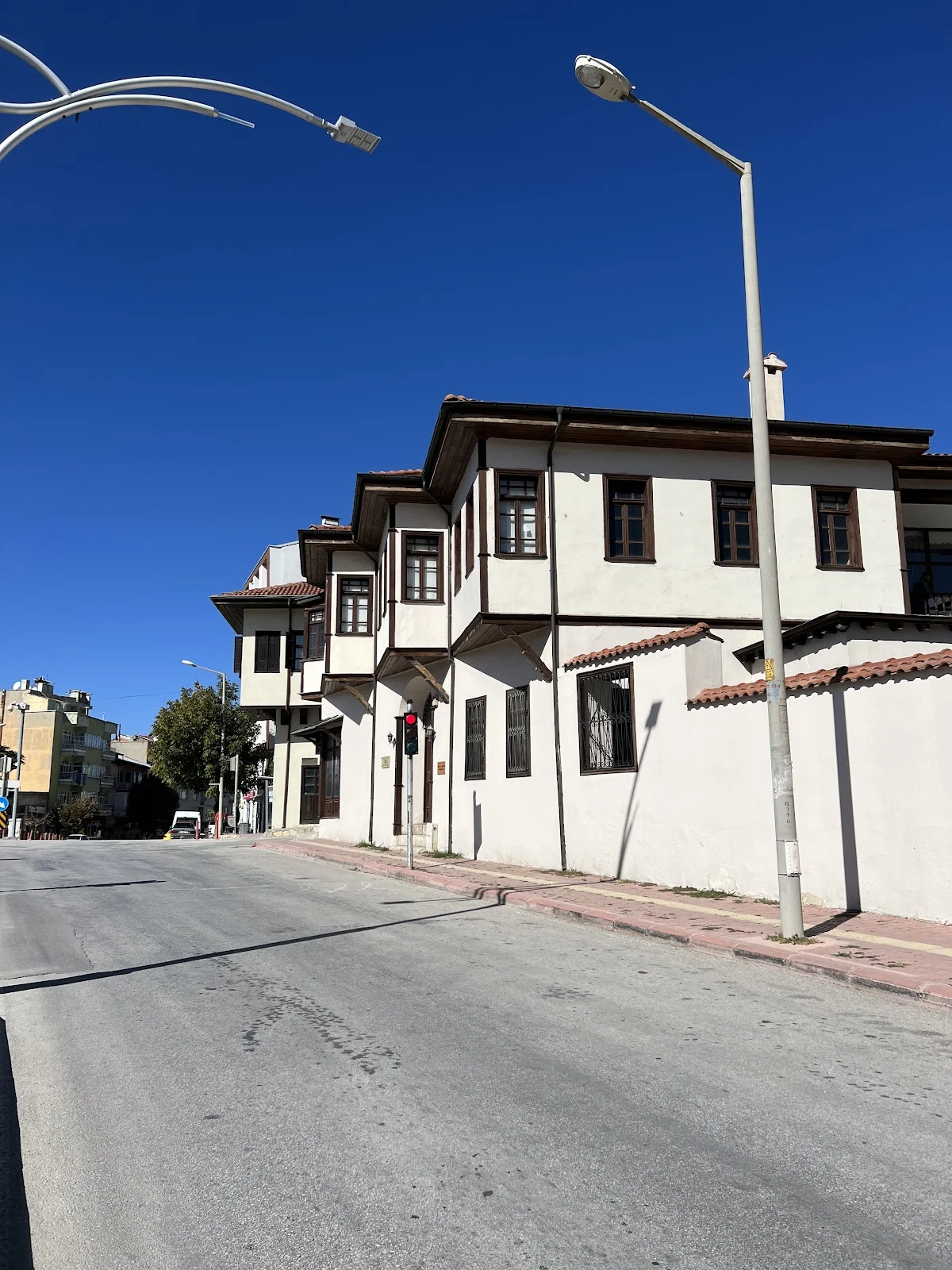 Geleneksel Mimarinin Modernle Buluşması - Piribaşlar Kültür ve Sanat Evi Geleneksel mimari yapıda beyaz duvarlar ve ahşap pencereler, modern şehir manzarasıyla birleşiyor.