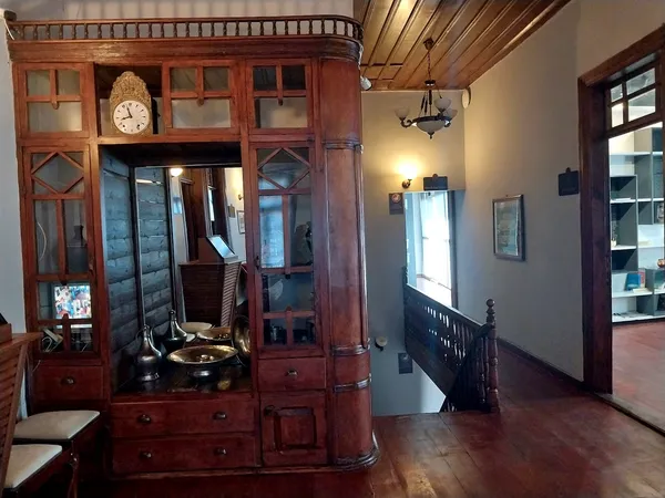 Tarihi iç mekanda ahşap dolap, metal süs eşyaları ve merdiven görünümü.