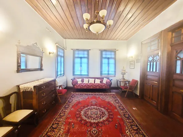 Tarihi oturma odası, ahşap tavan ve zeminle sıcak bir atmosfer sunuyor.