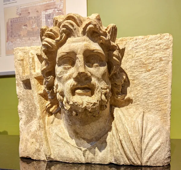 Antik bir erkeğin başı ve üst vücut kısmını tasvir eden heykel parçası, ciddi bir ifade ile dikkat çekiyor.