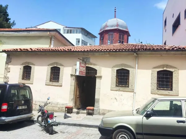 Tarihi yapının ön cephesi, açık renk taşlar ve çini kubbe ile dikkat çekiyor.