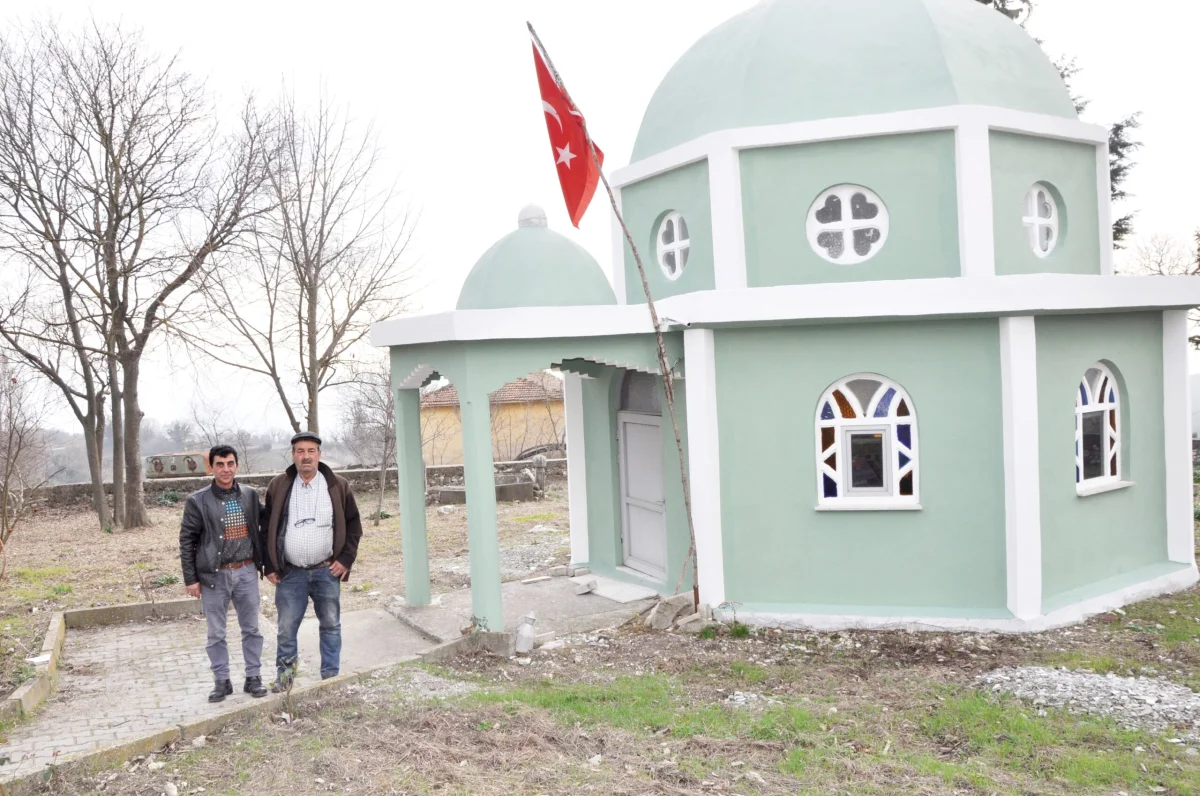 Doğanın İçinde Geleneksel Mimari - Yeşil kubbeli türbe ve Türk bayrağı İki kişi, arka planda Türk bayrağı dalgalanan yeşil kubbeli türbe ile birlikte duruyor.
