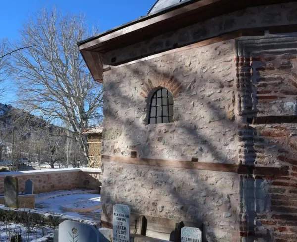 Tarihi Veli Dede Türbesi, karla kaplı zemin ve çevresindeki ağaçlarla görünmekte.