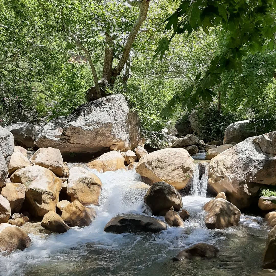Büyük doğal taşların arasında akan bir dere ve küçük bir şelale manzarası.