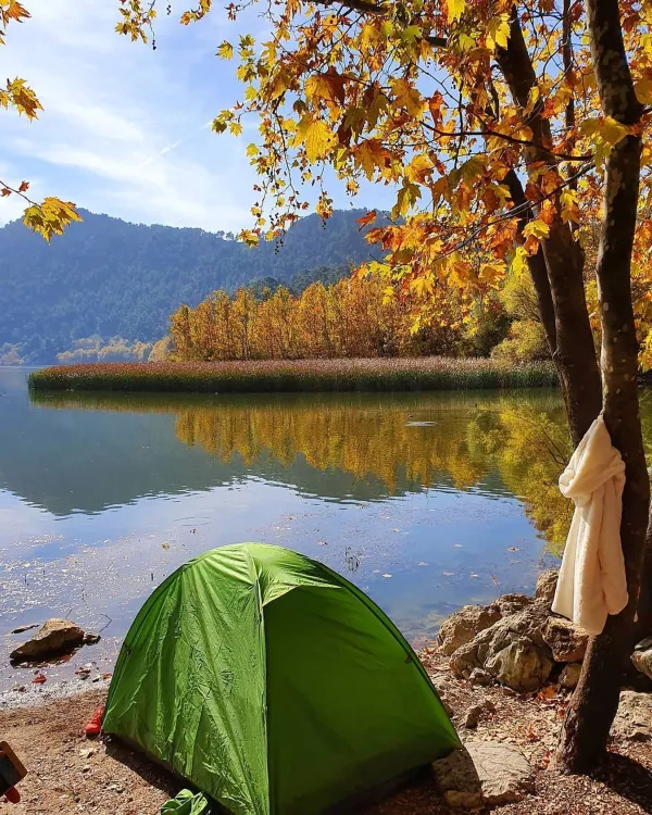 Yeşil çadır, sonbahar renkleriyle ağaçlar ve göl manzarası