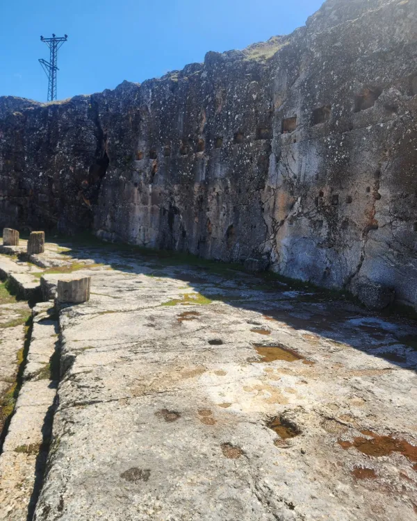 Antik kalıntılar, çatlaklı kayalık duvar ve taş döşeli zemin görüntüsü